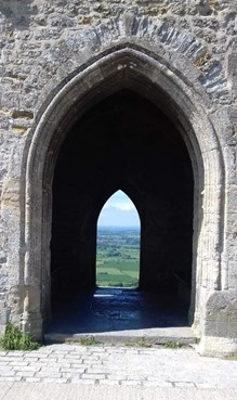 View through an arch of a historic building through to countryside in the background