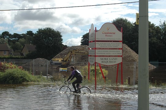 Cyclist in flooded road outside proposed development site