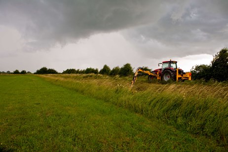 Digger clearing a watercourse in a rural setting